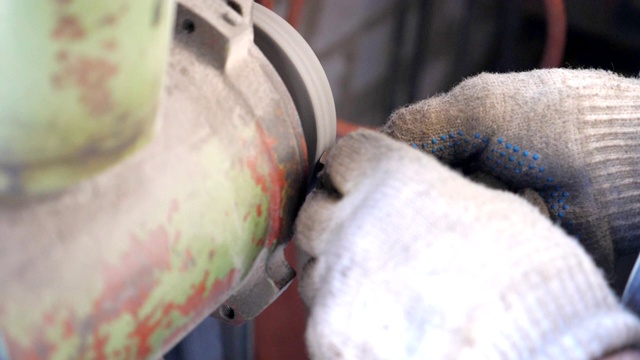 靠近手的男性机械与金属细节磨刀石上工作。在车库或车间工作的人。修理工磨铁。工人戴手套以确保安全。慢动作视频下载