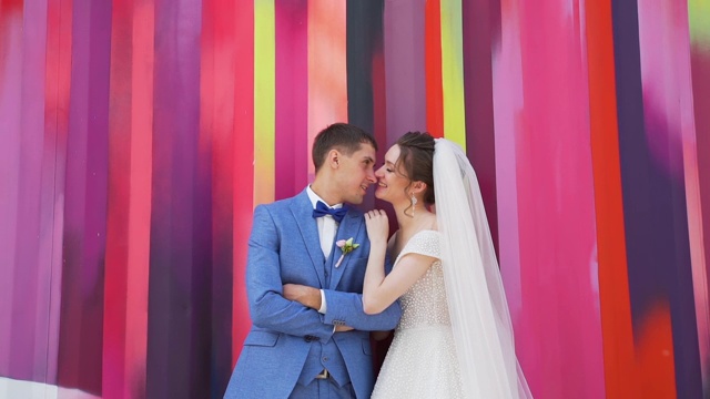 一对新婚夫妇靠在彩色的墙上视频下载
