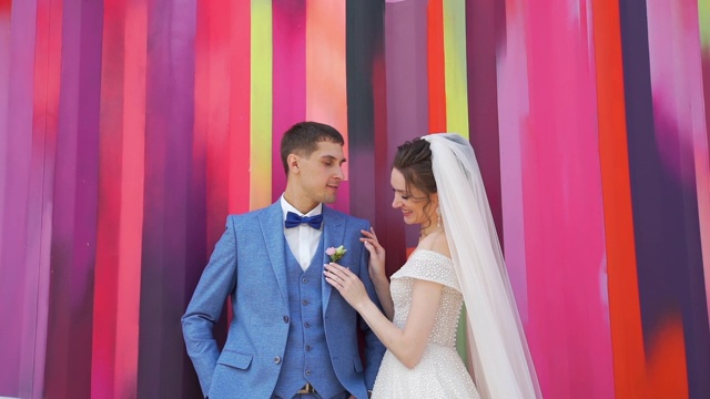 微笑的新婚夫妇在彩色墙附近交谈视频素材