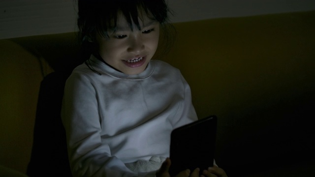 亚洲小女孩晚上用智能手机。视频素材