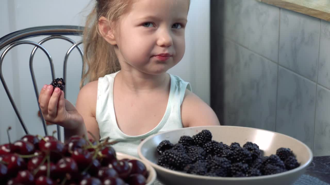 可爱的小女孩坐在厨房里吃黑莓视频下载