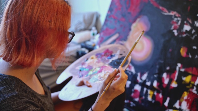 红发白人少女的肖像，艺术家，在她的房间里用油画画。视频素材