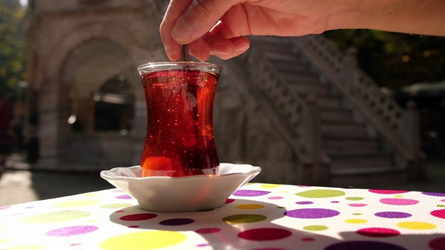 一个女人用勺子在一杯土耳其茶中慢动作地搅拌糖视频素材