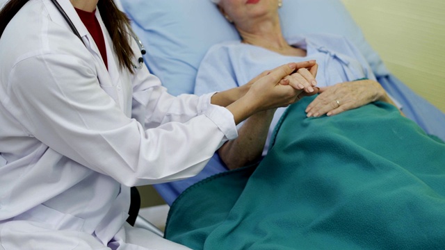 女护士医生牵着老祖母病人的手，帮助表达同情，鼓励告知诊断视频下载