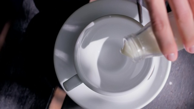 牛奶和茶倒进放在茶托上的茶杯里视频素材