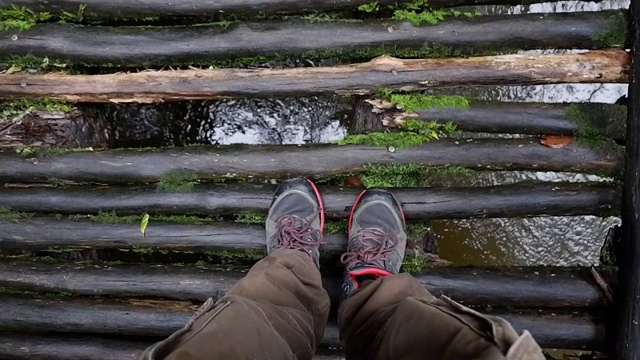 徒步旅行者的腿行走在腐朽的木桥上视频下载