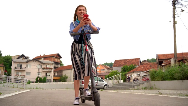 年轻女子骑着电动摩托车查看手机视频素材