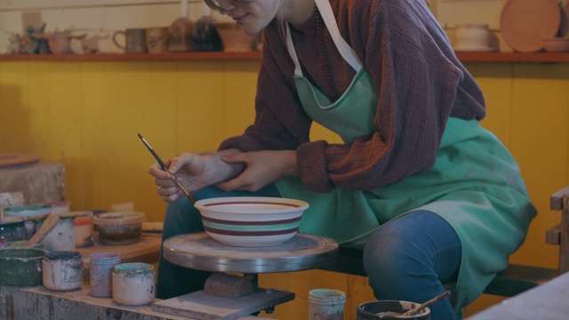年轻女子在她的陶艺工作室里画一只碗视频素材