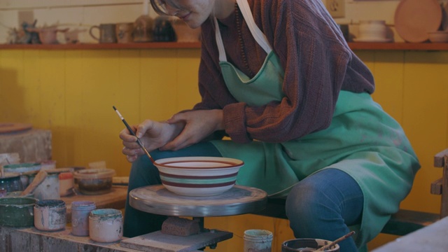 一名年轻女子在她的陶艺工作室里画一只碗视频素材