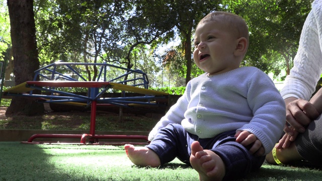 在公园里坐着一名不高兴的蹒跚学步的婴儿视频素材