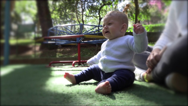 心烦意乱的蹒跚学步的婴儿坐在户外游乐场公园视频素材