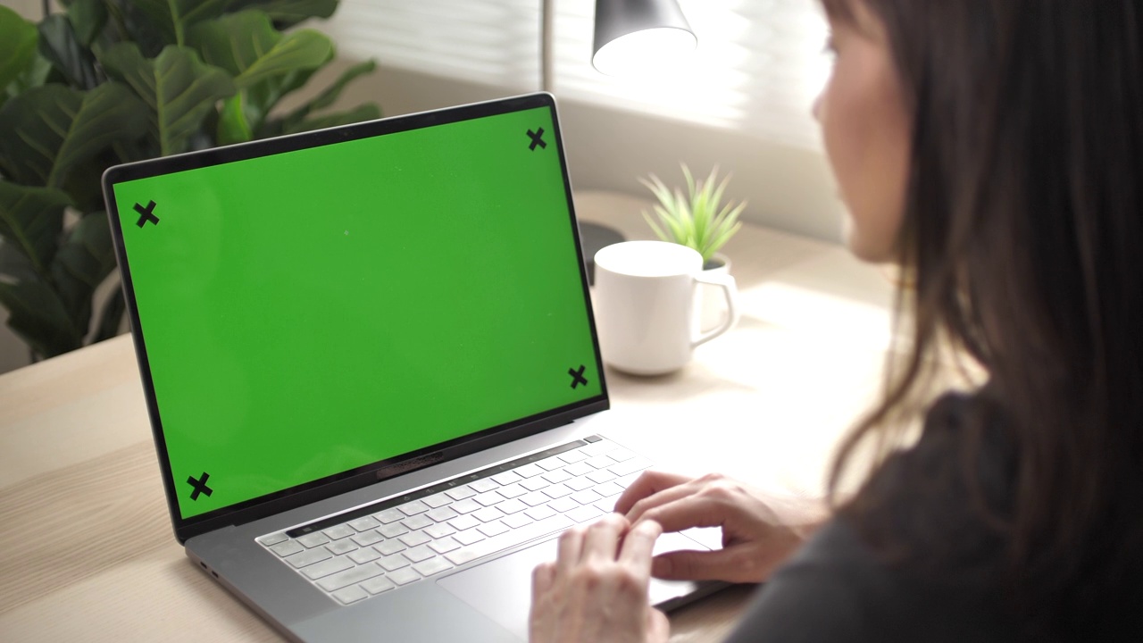 亚洲女人在家里的笔记本电脑上有绿色屏幕视频素材