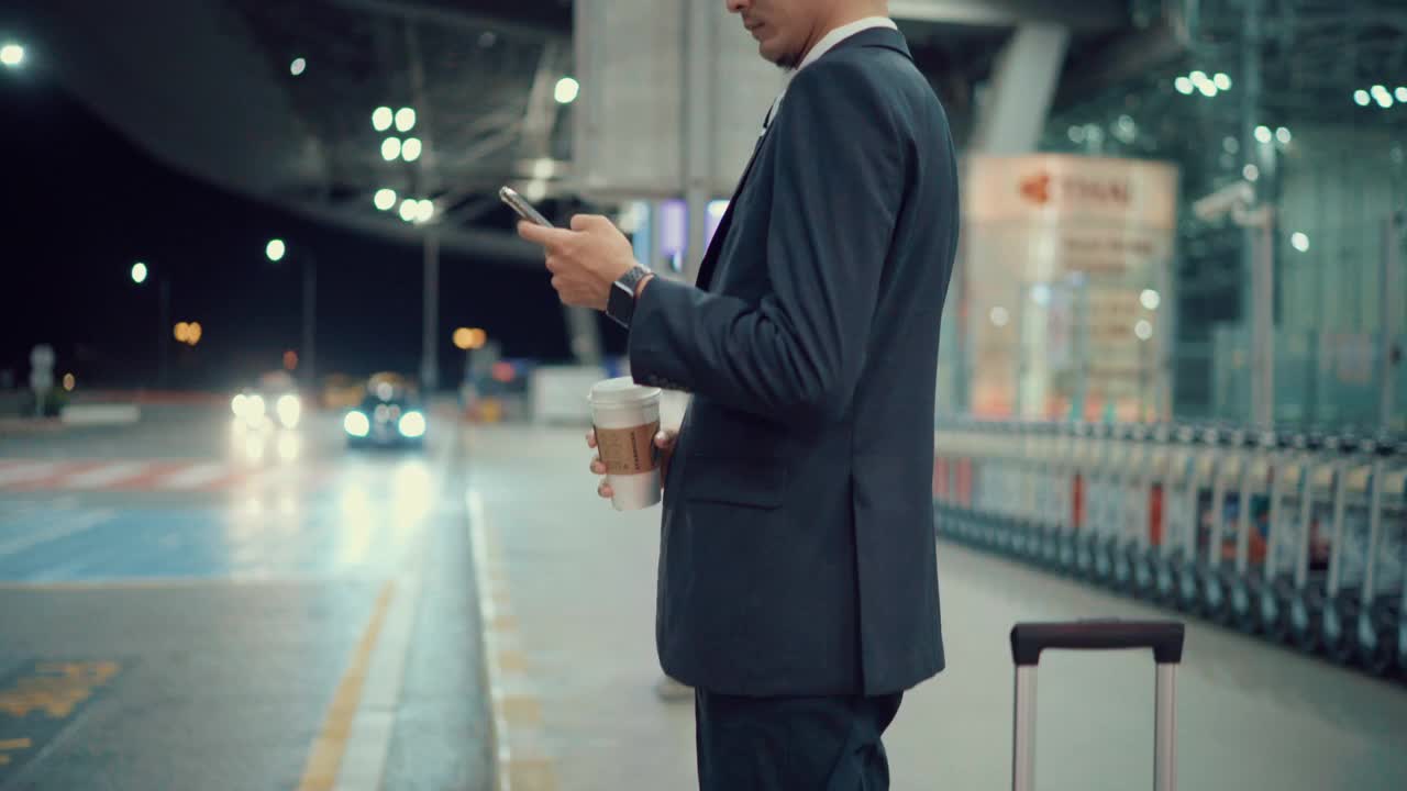 亚洲商人晚上用智能手机叫出租车视频下载
