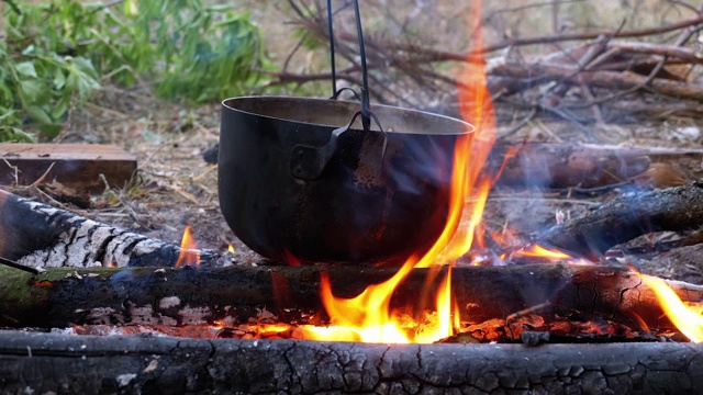 在一个旅游锅的火上烹饪。在篝火上挂的旅游圆顶礼帽视频素材