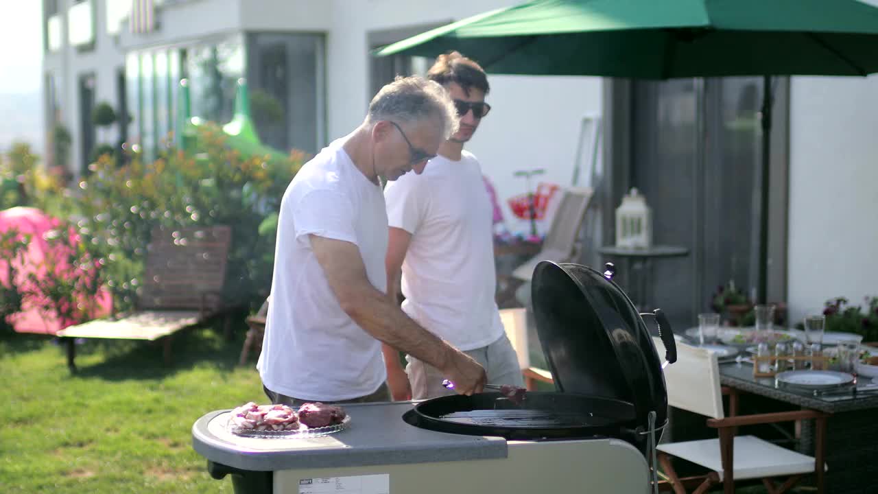 一家人在后院烧烤，父子俩在后院烧烤视频素材