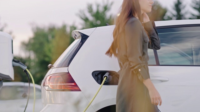 女子在充电站给她的车插电动汽车插头视频素材