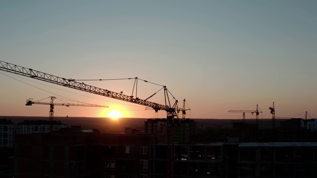 夕阳下的建筑起重机无人机视图。城市建筑工地。视频素材