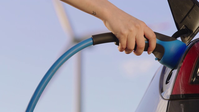 SLO MO手动拔出电动汽车插头，从一辆由风力涡轮机提供绿色能源的汽车视频素材