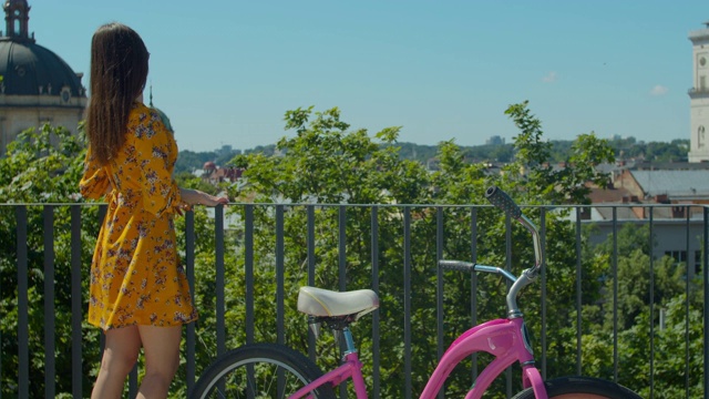 一幅迷人的年轻女子戴着太阳镜骑着自行车在公园里散步的肖像。美丽微笑的年轻女子肖像与自行车。视频素材