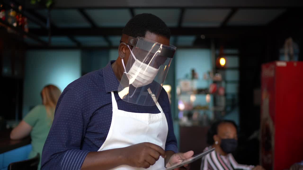 服务员在餐厅用数码平板电脑为顾客点菜——使用的是口罩视频下载