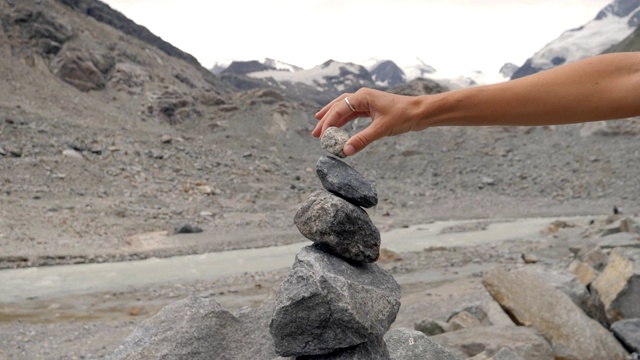 在Graubünden广东，瑞士拍摄的人在冰川附近的河流堆积岩石的细节。人的生活平衡理念视频素材
