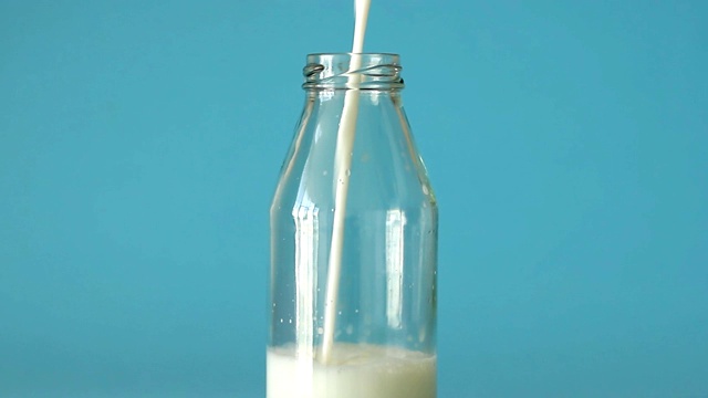 牛奶倒进一个玻璃瓶里。新鲜的农场牛奶对儿童的健康有好处，并能使身体充满钙和维生素D视频下载