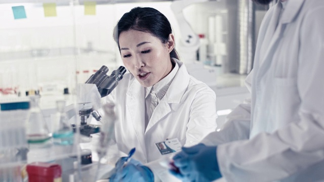 未来实验室。亚洲女医生使用显微镜，前景广阔视频素材