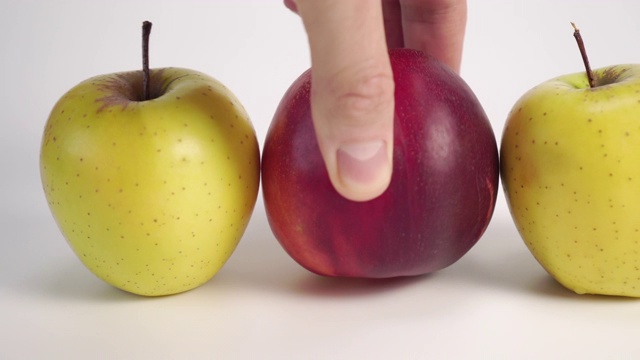 新鲜水果。一只手把成熟的红油桃插在白色桌子上的青苹果之间。视频下载