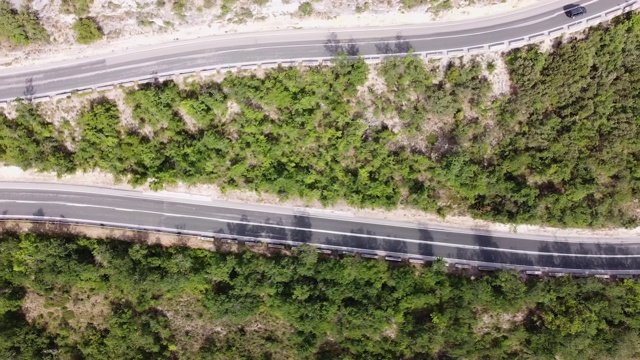 鸟瞰图蜿蜒的道路在高山口槽绿色松林。高质量的画面视频素材