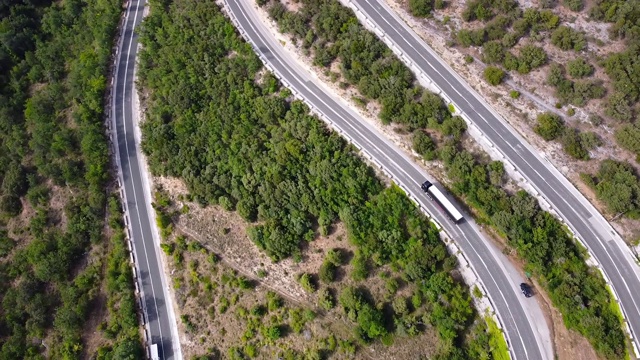 鸟瞰图蜿蜒的道路在高山口槽绿色松林。高质量的画面视频素材