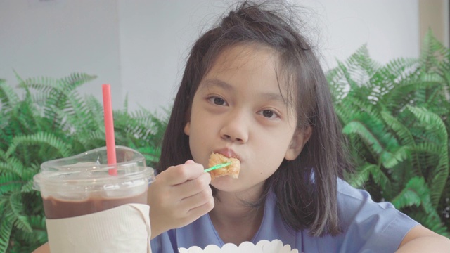 可爱的小女孩在咖啡馆吃牛角面包视频素材