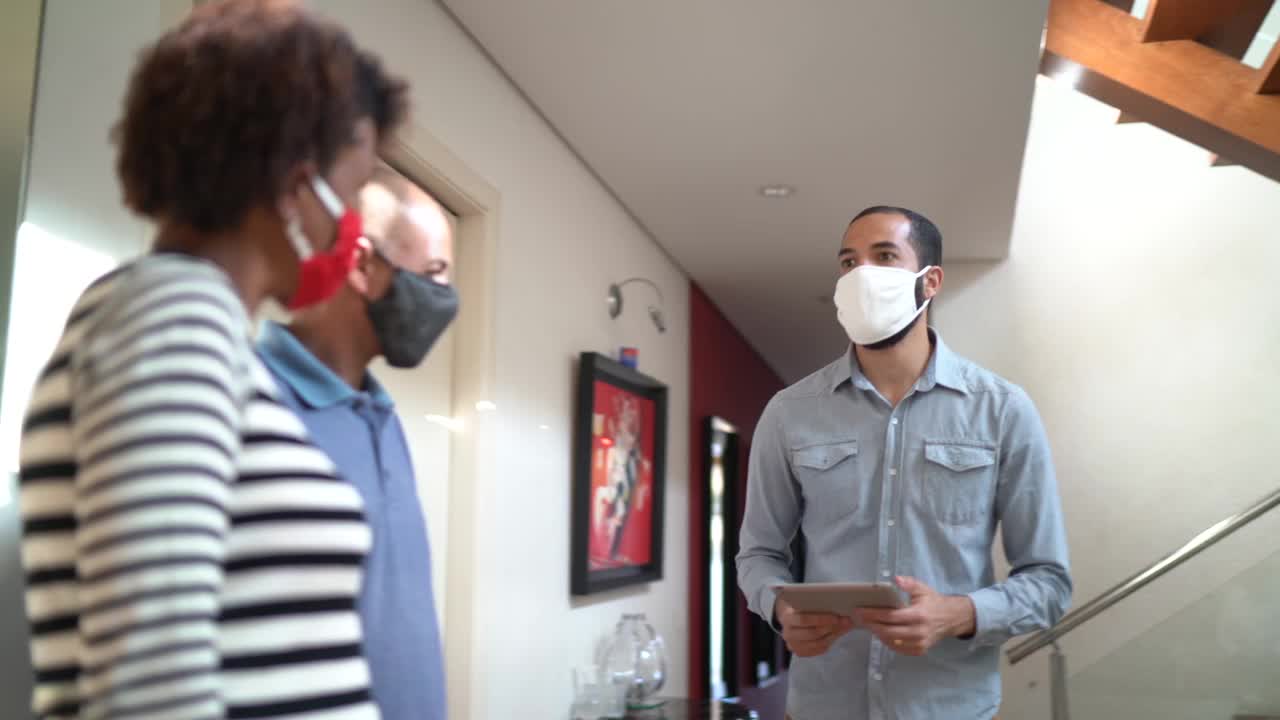 一对戴着口罩的夫妇参观一栋打折的房子视频下载
