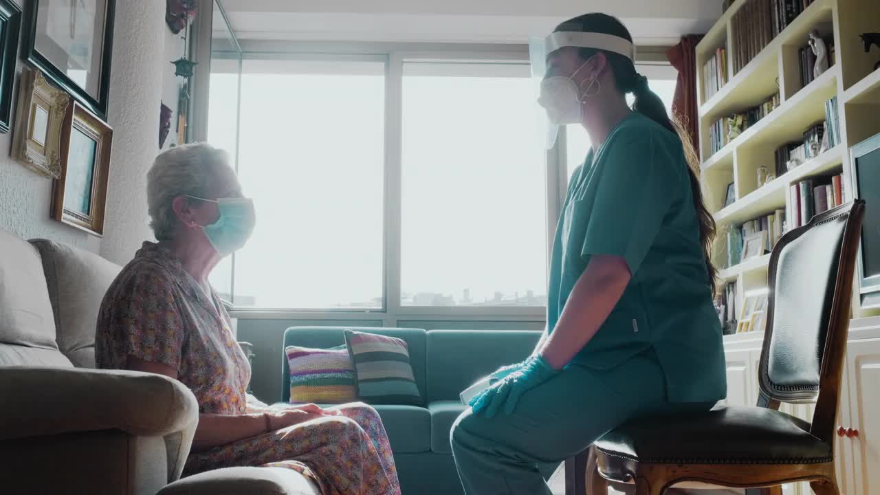 一名女护士为一名高级女性做体温检查。视频下载