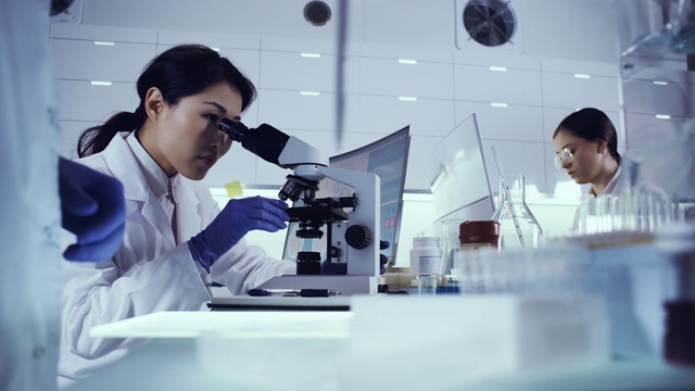 研究病原体样本的女性团队。亚洲医生使用显微镜视频素材
