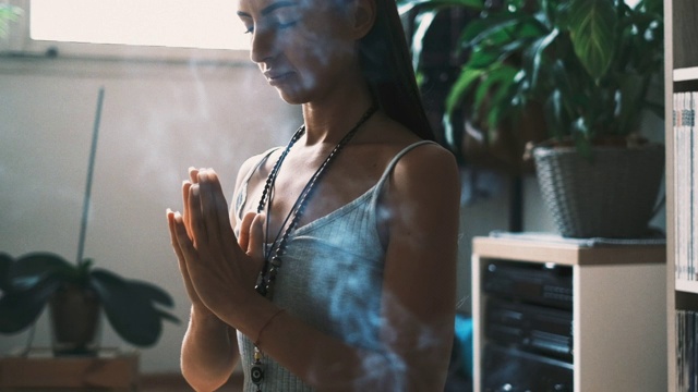 放松的年轻女子与她的眼睛闭着双手合十礼，而练习瑜伽和冥想在家视频下载