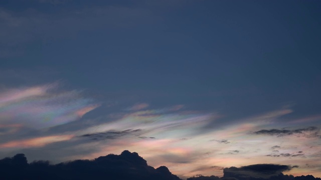 美丽的彩虹云之上的乌云快速移动在天空在晚上。视频下载