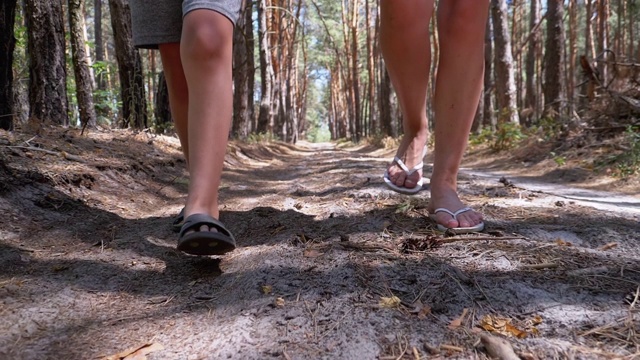 夏天，年轻母亲和儿子在森林小径上散步的双腿。慢动作视频素材
