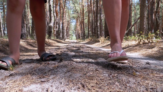 夏天，年轻母亲和儿子在森林小径上散步的双腿。慢动作视频素材