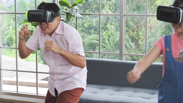 爸爸和女儿戴着虚拟现实眼镜一起玩电子游戏。视频下载