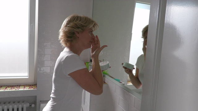在浴室里拿着罐子涂面霜的女人视频素材