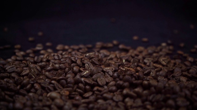 咖啡豆落在黑色背景上的慢镜头视频素材