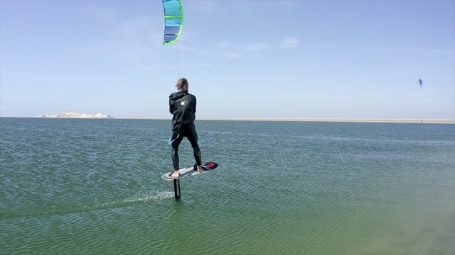 男子风筝滑板上的水翼箔在一个风筝板附近的海滩。视频下载