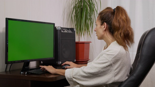 这是一个女人在绿色屏幕的笔记本电脑键盘上打字的照片，在家里工作，家庭办公室的人使用彩色键的笔记本电脑绿色屏幕。视频下载