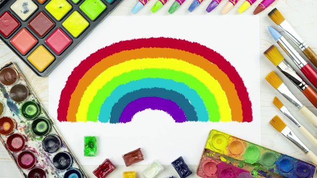 彩虹绘制动画在一个平铺画背景与白纸，调色板水彩颜料，画笔，彩色粉笔，儿童的背景俯视图视频下载