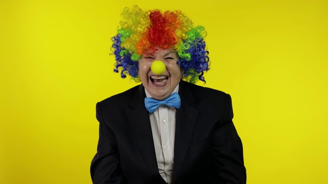 小丑老婆婆戴着五颜六色的假发笑着，胡闹着，笑着。万圣节视频下载