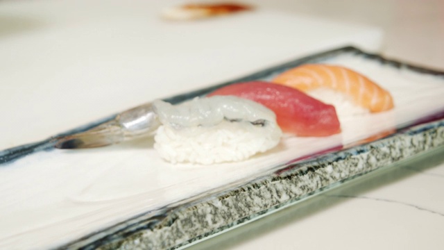 美味的生鱼片与米饭，鱼和虾在盘子上的特写。厨师的手端上寿司卷视频下载