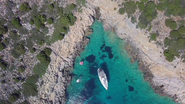 一艘帆船停泊在希腊斯基亚索斯的V形海湾的无人机图片。视频素材