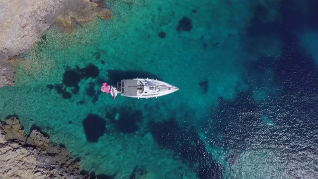 一艘帆船停泊在希腊斯基亚索斯的V形海湾的无人机图片。视频下载