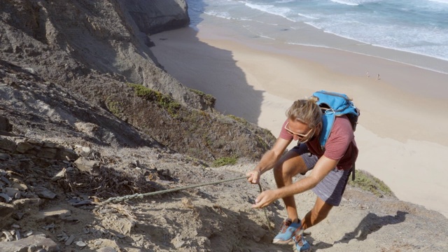 男性攀登者爬上岩壁，伸手相助。同伴帮助攀登者到达顶峰视频下载