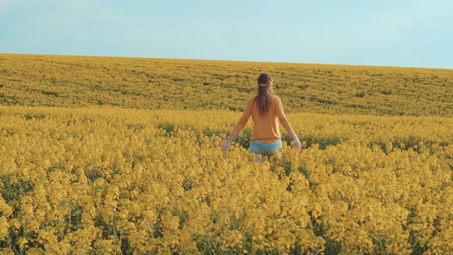 快乐的女人在黄花盛开的油菜地里奔跑。过敏的自由概念。视频素材